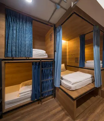 two bunk beds in a room with blue curtains at Natee Hostel in Bangkok