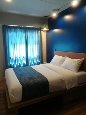 a bedroom with a large bed with a blue wall at Natee Hostel in Bangkok