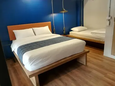 a bedroom with a large bed and a blue wall at Natee Hostel in Bangkok