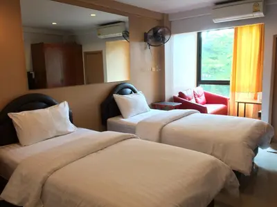a hotel room with two beds and a red chair at Chanmuan Resident in Bangkok