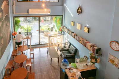 a room with a staircase and a person sitting at a table at Phobphan Hostel in Bangkok