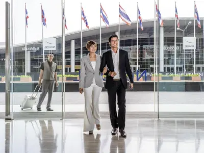 a man and a woman walking in front of a building at Novotel Bangkok IMPACT in Nonthaburi