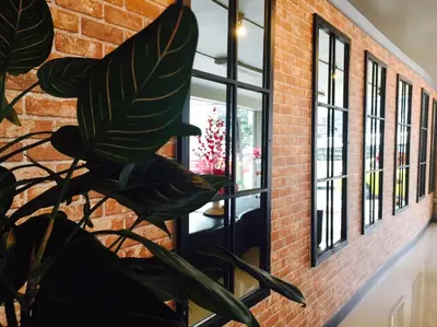 a brick wall with windows and a plant at The Corner Ratchada in Bangkok
