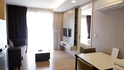 a living room with a table and a television in a room at 18 Residence in Bangkok