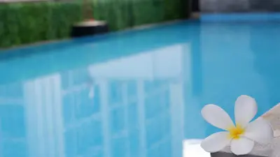 a white flower sitting next to a swimming pool at 18 Residence in Bangkok