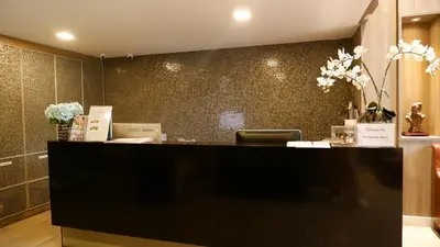 a lobby with a reception desk with flowers on the wall at 18 Residence in Bangkok
