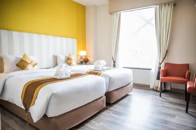 a hotel room with two beds and a red chair at Bangkok Midtown Hotel in Bangkok