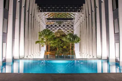a large swimming pool in a building with palm trees at Bangkok Midtown Hotel in Bangkok