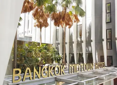 a sign in front of a building with palm trees at Bangkok Midtown Hotel in Bangkok