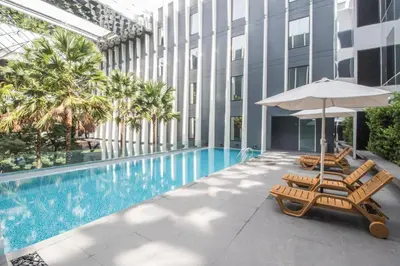 a swimming pool with two lounge chairs and an umbrella at Bangkok Midtown Hotel in Bangkok