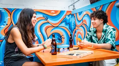 two women sitting at a table with a bottle of beer at Bodega Bangkok Soi 23 in Bangkok