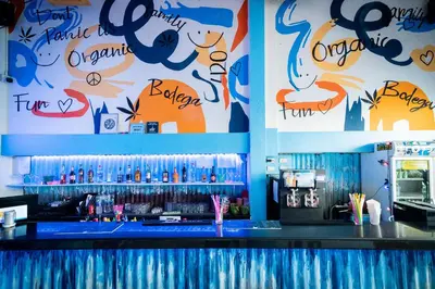 a bar with a blue counter with drinks on the wall at Bodega Bangkok Soi 23 in Bangkok