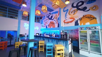 a restaurant with a bar with colorful tables and stools at Bodega Bangkok Soi 23 in Bangkok