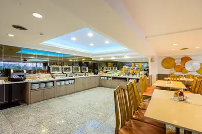 a restaurant with tables and chairs and a kitchen at Samran Place Hotel in Bangkok