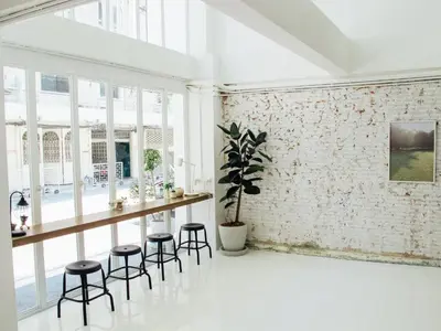 a white room with a table and stools at Varmtel in Bangkok