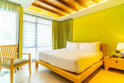 a bedroom with yellow walls and a bed and a chair at Amber Boutique Silom in Bangkok