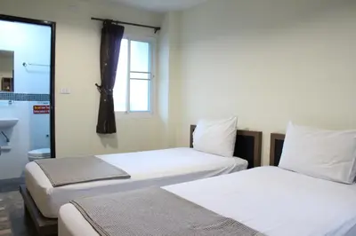 two beds in a room with a window at Samsen Sam Place in Bangkok