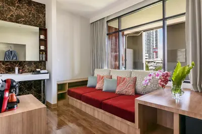 a living room with a couch with a red cushion at VELA be Bangkok Ratchathewi in Bangkok