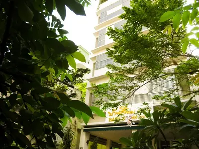 a tall white building with trees in front of it at Baansilom Soi 3 in Bangkok