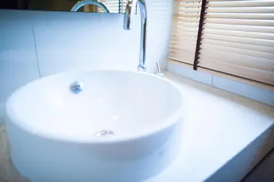 a white sink in a bathroom with a window at Baansilom Soi 3 in Bangkok