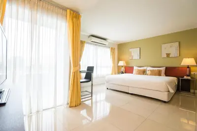 a bedroom with a bed and a chair and a window at Beyond Suite in Bangkok