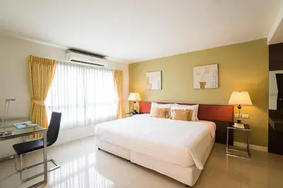 a bedroom with a large white bed and a window at Beyond Suite in Bangkok