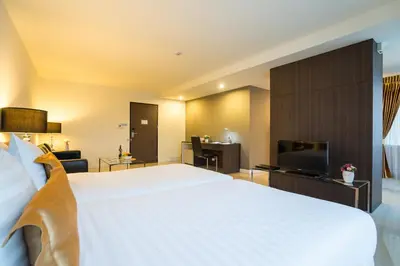a bedroom with a large white bed and a television at Beyond Suite in Bangkok