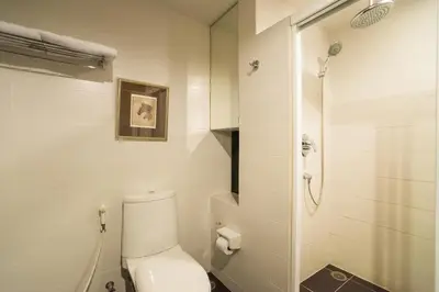 a white bathroom with a toilet and a shower at Beyond Suite in Bangkok