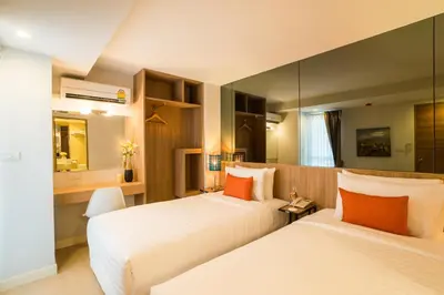 a hotel room with two beds and a mirror at Beyond Suite in Bangkok