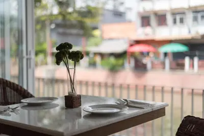 a table with two plates and a vase with a plant at Casa Vimaya Riverside in Bangkok