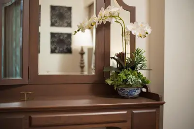 a mirror and a vase with flowers on a dresser at Casa Vimaya Riverside in Bangkok