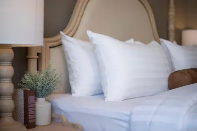a bed with white pillows and a plant on a table at Casa Vimaya Riverside in Bangkok