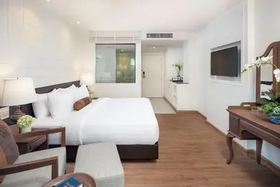a bedroom with a large white bed and a television at Casa Vimaya Riverside in Bangkok