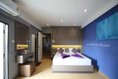 a bedroom with a bed and a blue wall at Kaya Place in Bangkok