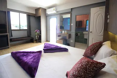 a bedroom with a large bed with purple pillows on it at Kaya Place in Bangkok