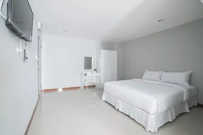 a white bedroom with a bed and a flat screen tv at S44ROOM in Bangkok