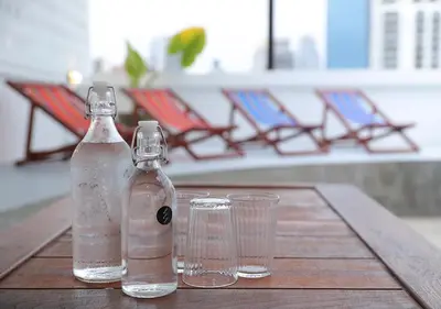 two bottles and two glasses on a wooden table at Apartment45 Hostel in Bangkok