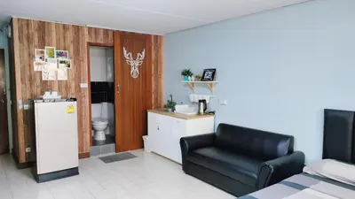 a living room with a black chair and a kitchen at Nesto Condo at Muangthong in Pak Kret