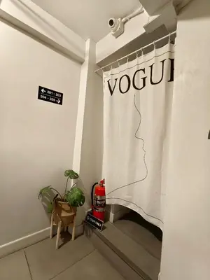 a room with a curtain that says vogu on the wall at 101 SEOUL HOSTEL (101 โซล โฮสเทล) in Bangkok