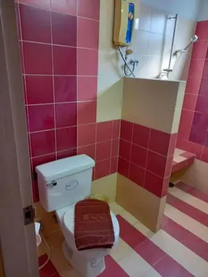 a pink bathroom with a toilet and a sink at Mansion Sarasinee @ Chatuchak in Bangkok