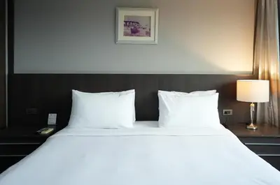 a large bed with white pillows in a hotel room at Royal Suite Hotel Bangkok in Bangkok