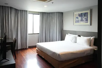 a hotel room with a bed and a desk and a window at Royal Suite Hotel Bangkok in Bangkok