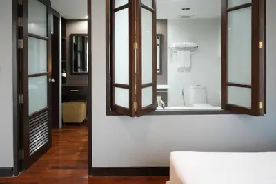 a room with a mirror and a bathroom with a toilet at Royal Suite Hotel Bangkok in Bangkok