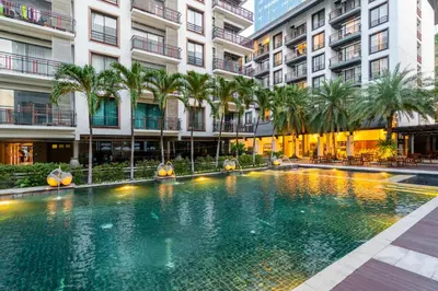a swimming pool in the middle of a building with palm trees at Amanta Hotel & Residence Ratchada in Bangkok