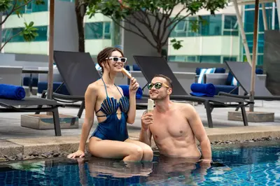 a man and a woman sitting in a swimming pool at Park Plaza Bangkok Soi 18 in Bangkok