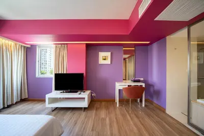 a bedroom with purple walls and a bed and a tv at Veronica Residence in Bangkok