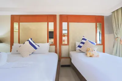 two beds in a room with a teddy bear sitting on them at Diamond City Hotel SHA Certified in Bangkok