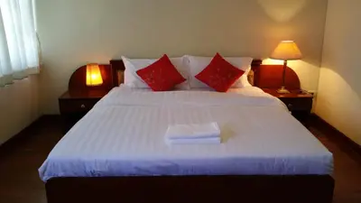 a bedroom with a large white bed with red pillows at Poonchock Mansion in Bangkok
