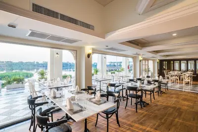 a restaurant with tables and chairs and large windows at Kalanan Riverside Resort in Nonthaburi