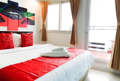 a bedroom with a red and white bed and a window at Khaosan Art Hotel in Bangkok